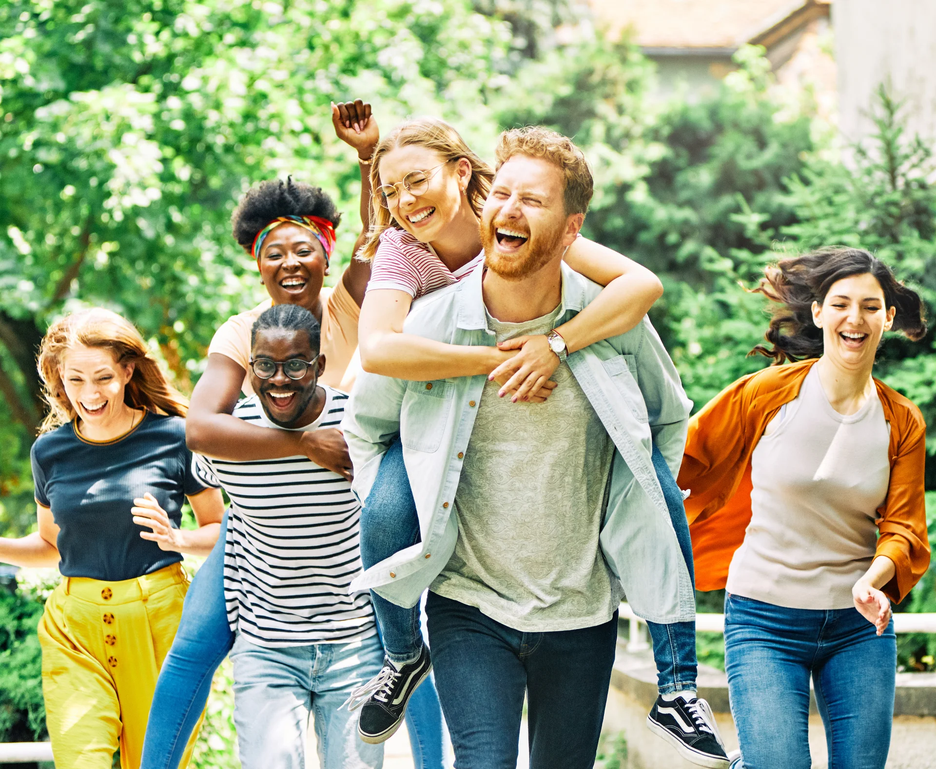 Group of diverse friends joyfully running outdoors, showcasing camaraderie and support, reflecting community spirit in recovery.