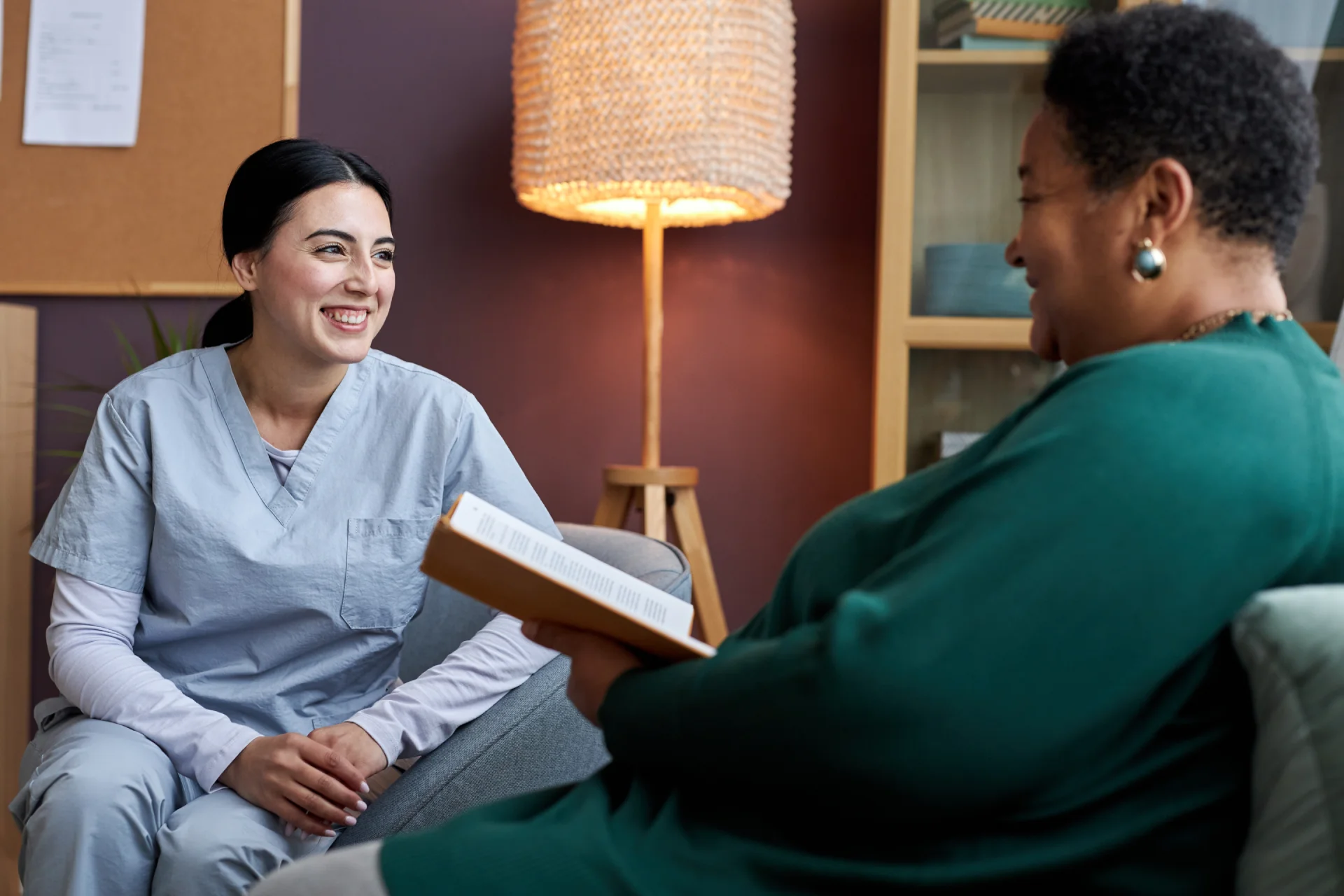 Healthcare professional engaging in supportive conversation with a client in a cozy, therapeutic setting, emphasizing personalized care in addiction recovery.