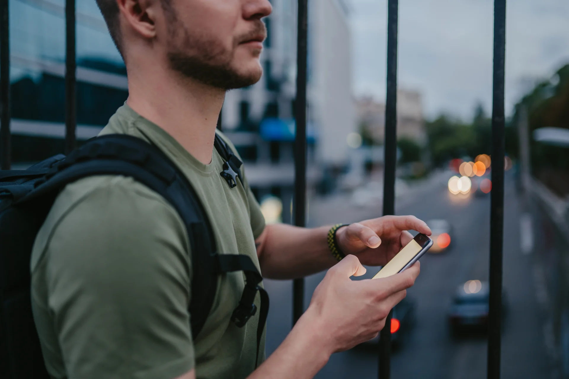 Man using smartphone near railing, symbolizing telehealth accessibility for addiction treatment and virtual support.