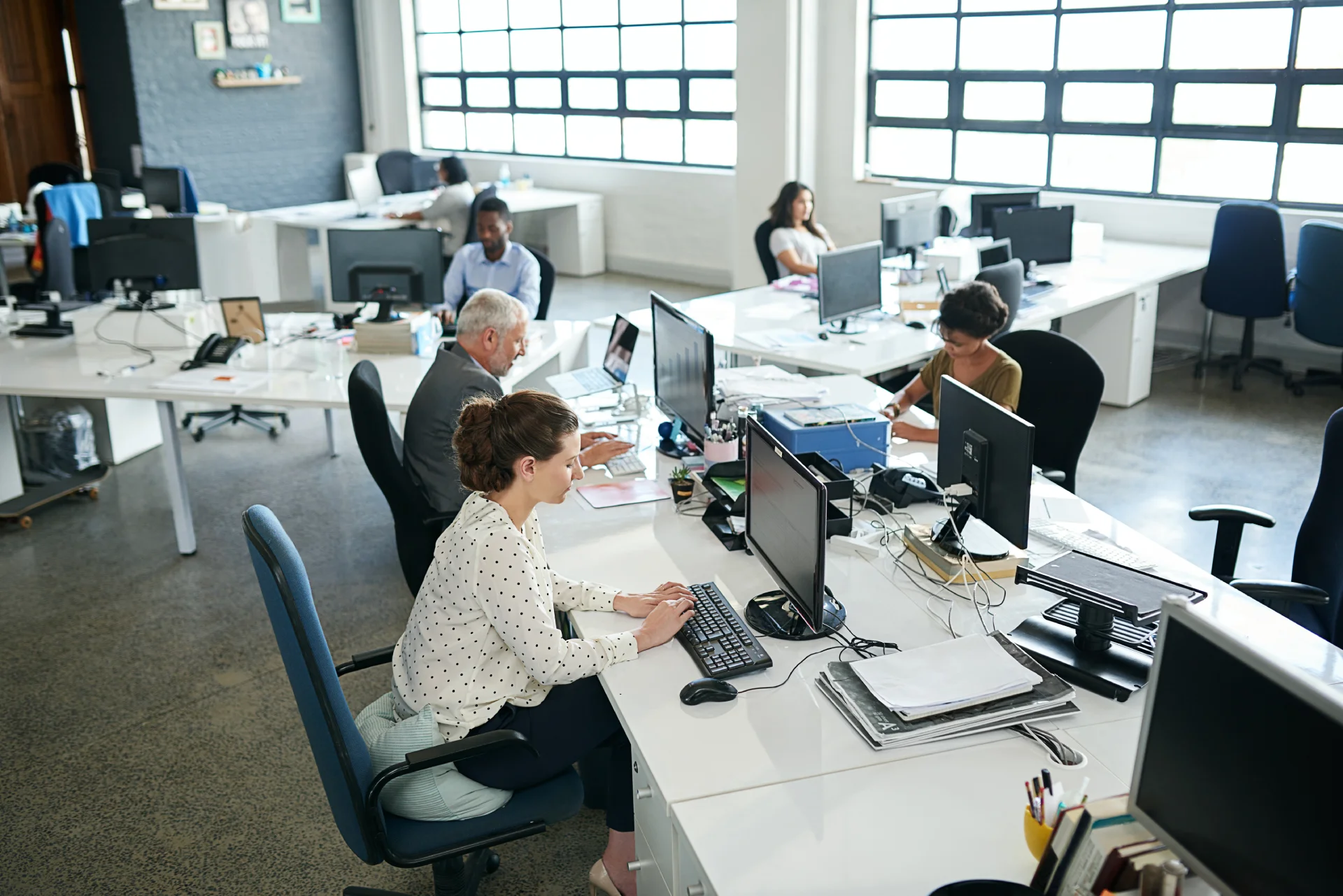 Office environment with multiple individuals working at desks, focusing on mental health and addiction treatment services at Hudson Valley Addiction Treatment Center.